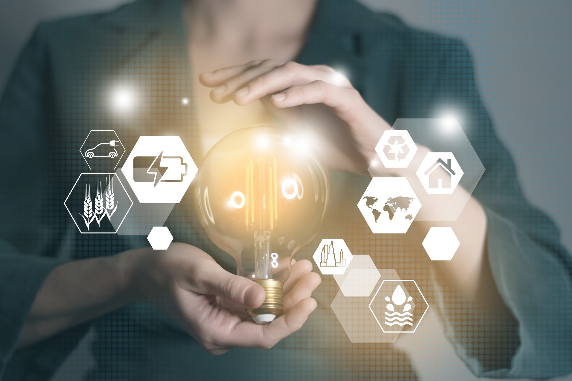 Energy innovation light bulb with future industry of power generation icons graphic interface in woman`s hands. Concept of sustainability development and alternative energy.